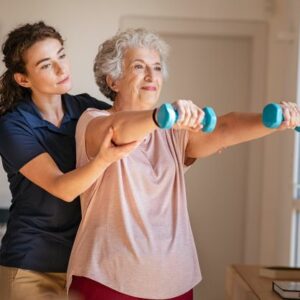 trainer helping older lady lift small weights